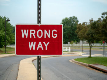 Road sign by street against sky