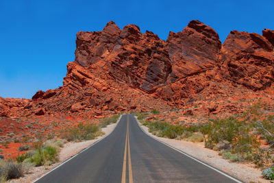 Empty road leading towards rocky mountain