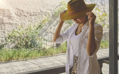 Young woman wearing hat standing against trees