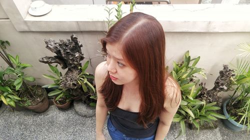 High angle view of young woman standing by potted plants