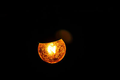 Close-up of illuminated lighting equipment against black background