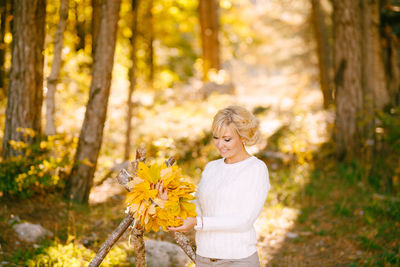 Woman standing by yellow flower in forest
