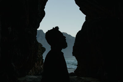 Silhouette man standing in a cave.