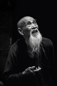 Portrait of man sitting against black background