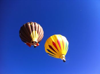 Low angle view of balloons flying against blue sky