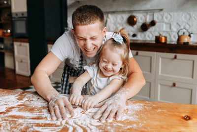 Funny happy dad and daughter baby cook together fool around and play with flour in  kitchen at home