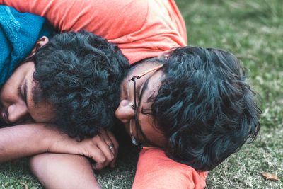 Close-up of friends relaxing on grassy field