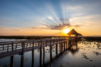 Pier over sea against sky during sunset