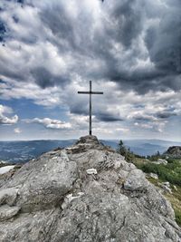 Cross on rock by sea against sky