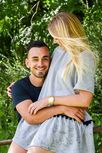 Happy young couple by railing at park