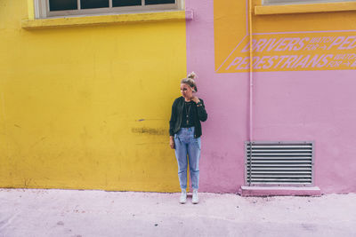 Full length of young woman standing against wall