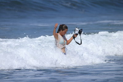 Woman holding camera in sea