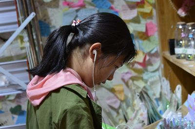 Side view of girl listening music on headphones at store