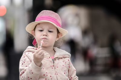 Girl wearing hat while looking at lollipop