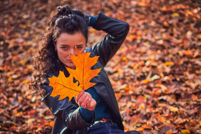 Young man with autumn leaves on field