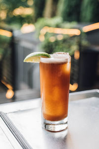 Tamarind whiskey sour in tall collins glass with lime wedge