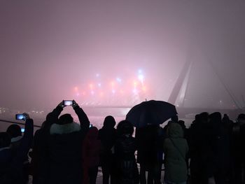 Silhouette people at music concert against sky at night