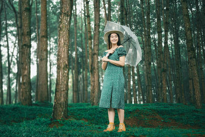 Full length of woman standing amidst trees in forest