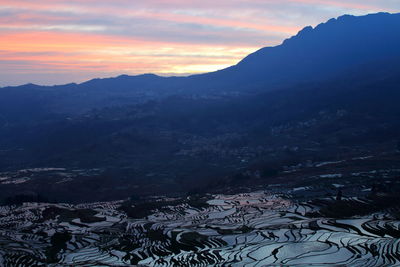 High angle view of snowcapped mountains against sky during sunset