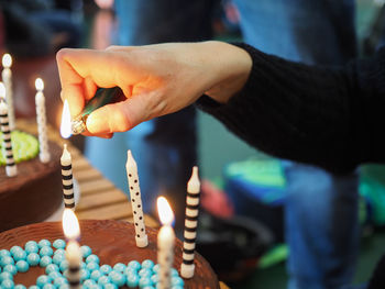 Close-up of hand lighting candles on cake