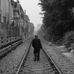 Rear view of man walking on railway tracks