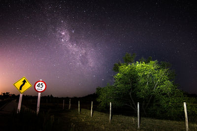 Road sign on field against star field at night