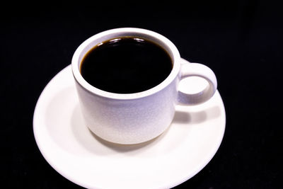 Close-up of coffee cup on table against black background