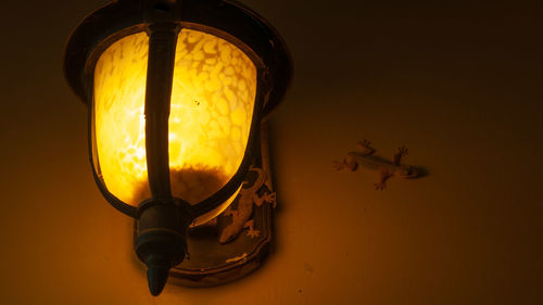 Close-up of illuminated light bulb against wall