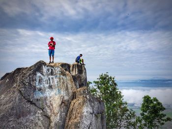 Men standing on cliff against sky