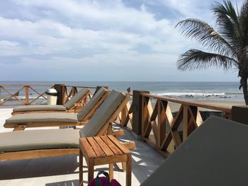 Chairs and tables on beach against sky