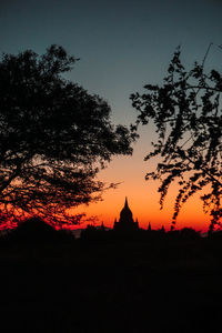 Silhouette trees and buildings against sky during sunset