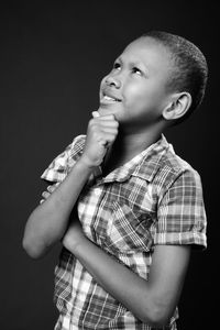 Side view of boy looking away against black background