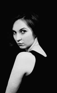 Close-up portrait of young woman over black background