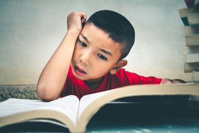 Portrait of boy on book at home