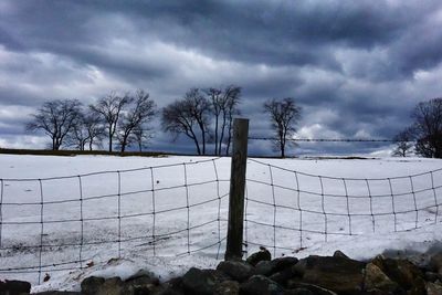 Snow covered landscape against cloudy sky