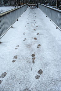 High angle view of shoe prints on snow covered footbridge