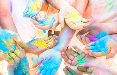 Cropped hands of friends with colorful powder paints