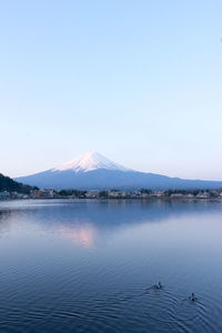 Scenic view of lake by snowcapped mountains against clear sky