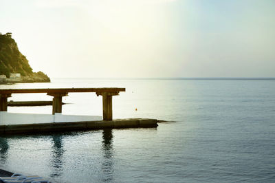 Sunrise on the sea with sun glare, pier on the shore in the early morning, calm, rest, summer 