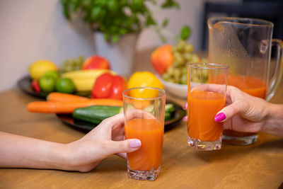 Cropped hand of woman holding drink on table