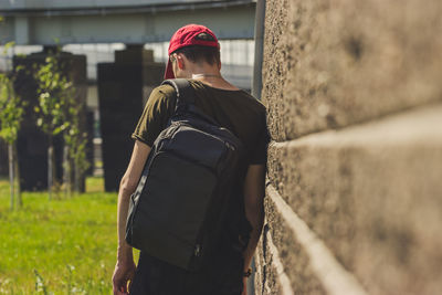 Rear view of man standing by wall outdoors