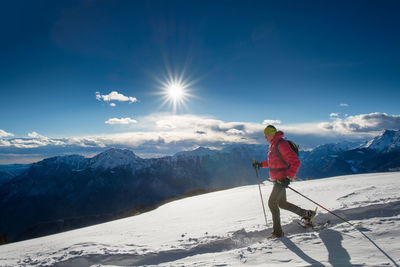 Rear view of man skiing on snowcapped mountains against sky