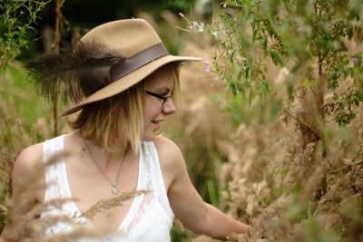 Young woman wearing hat standing against trees