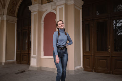 Portrait of young woman standing against building