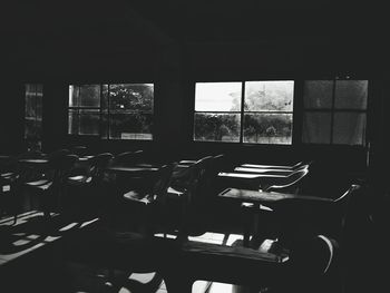 Empty chairs and table against window