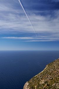 Scenic view of sea against vapor trails in sky