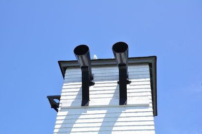 Low angle view of cross on building against clear blue sky