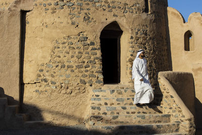 Rear view of woman standing against old building