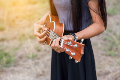 Midsection of woman playing guitar