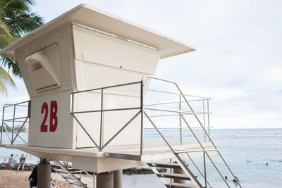 Information sign by sea against sky